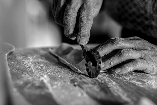 Black and white close-up of hands skillfully crafting homemade pasta.