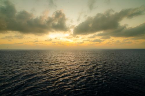 Free Peaceful ocean sunset with dramatic clouds and vivid colors. Captures tranquility and natural beauty. Stock Photo