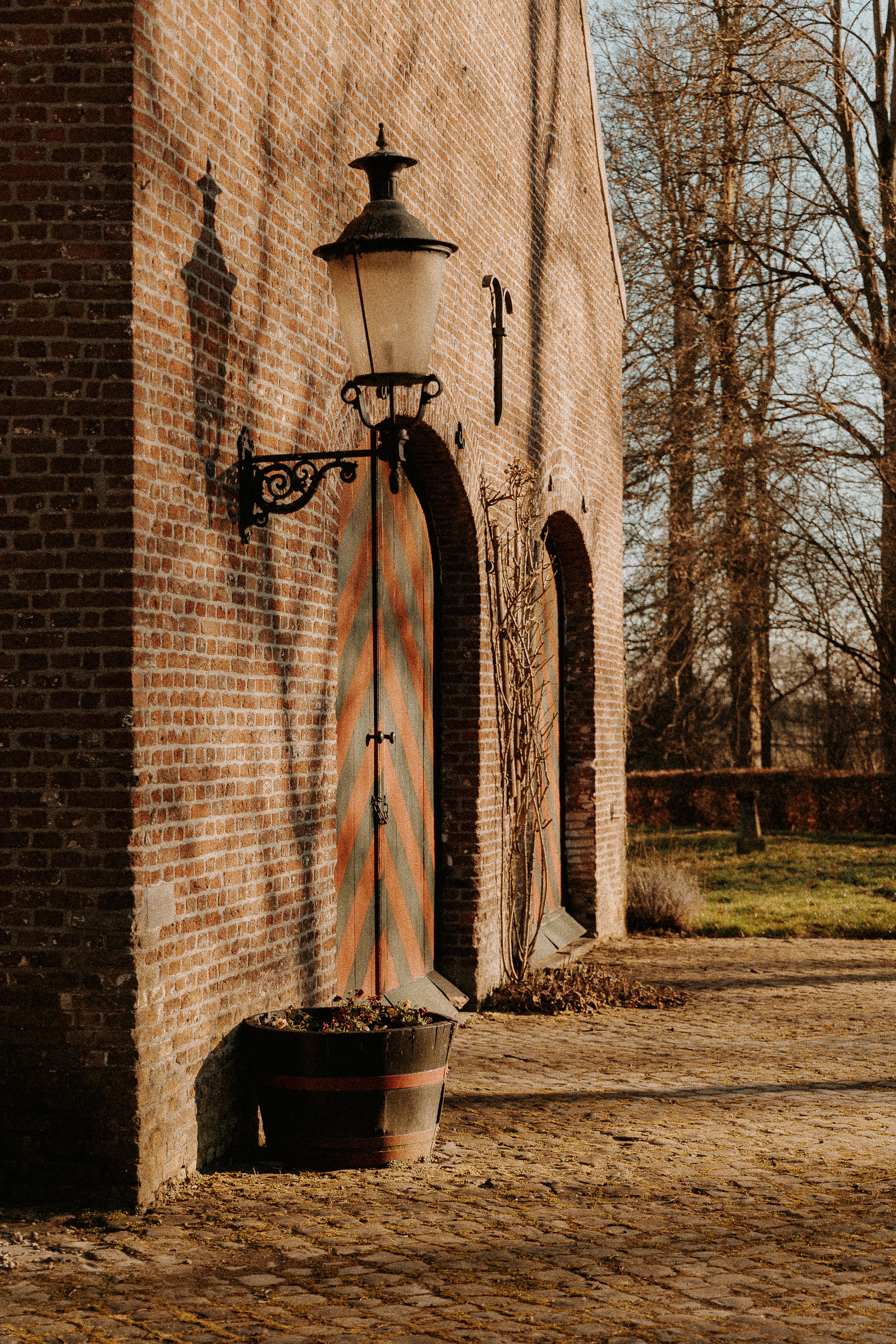 Rustic brick wall with vintage lamp and striped door, capturing countryside charm.