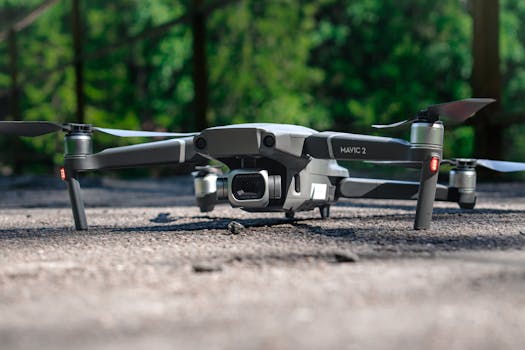 Close-up of a Mavic 2 drone resting on the ground, surrounded by nature in daylight.