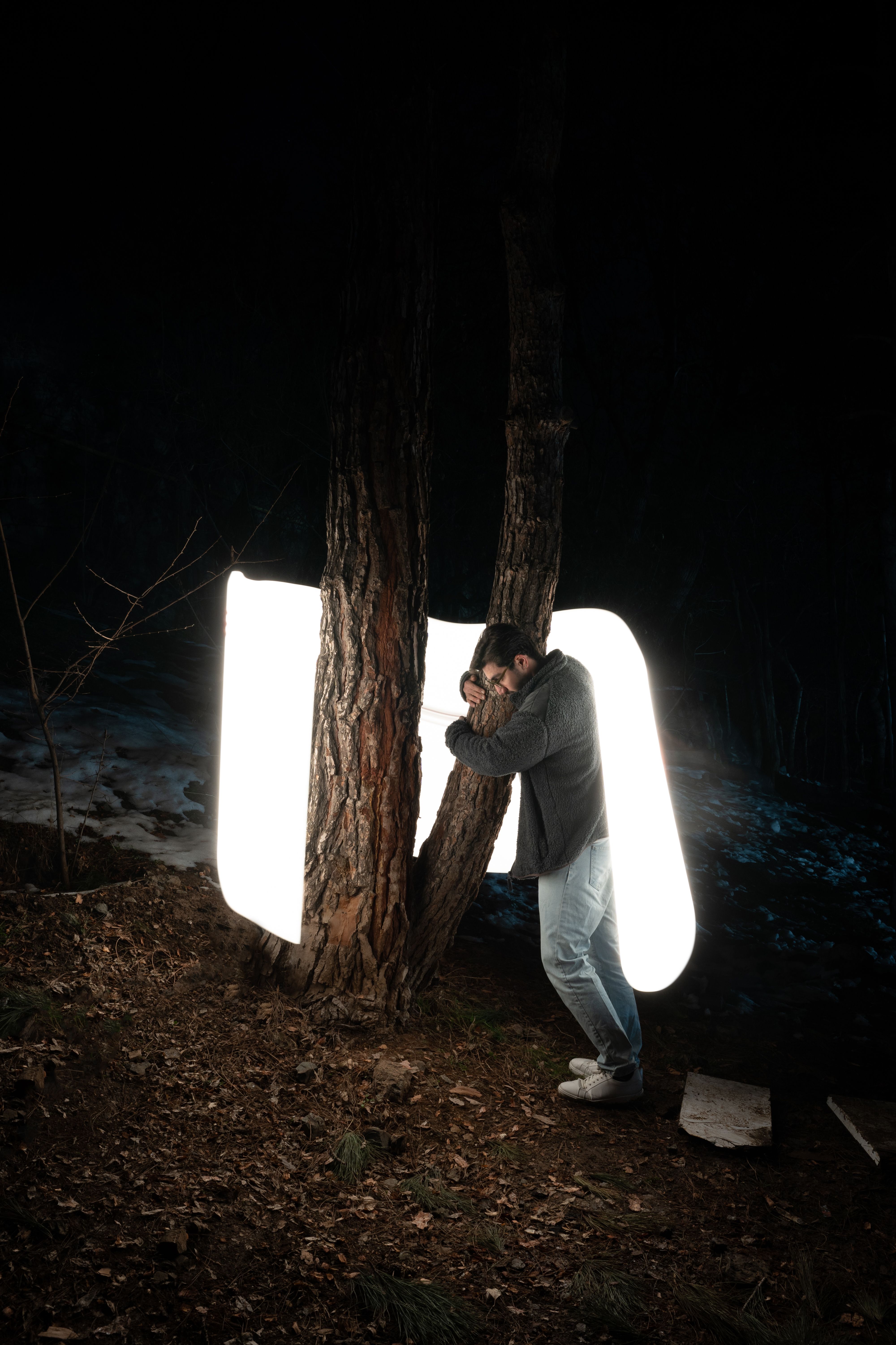 Man creates art with light painting in a Tehran forest at night.