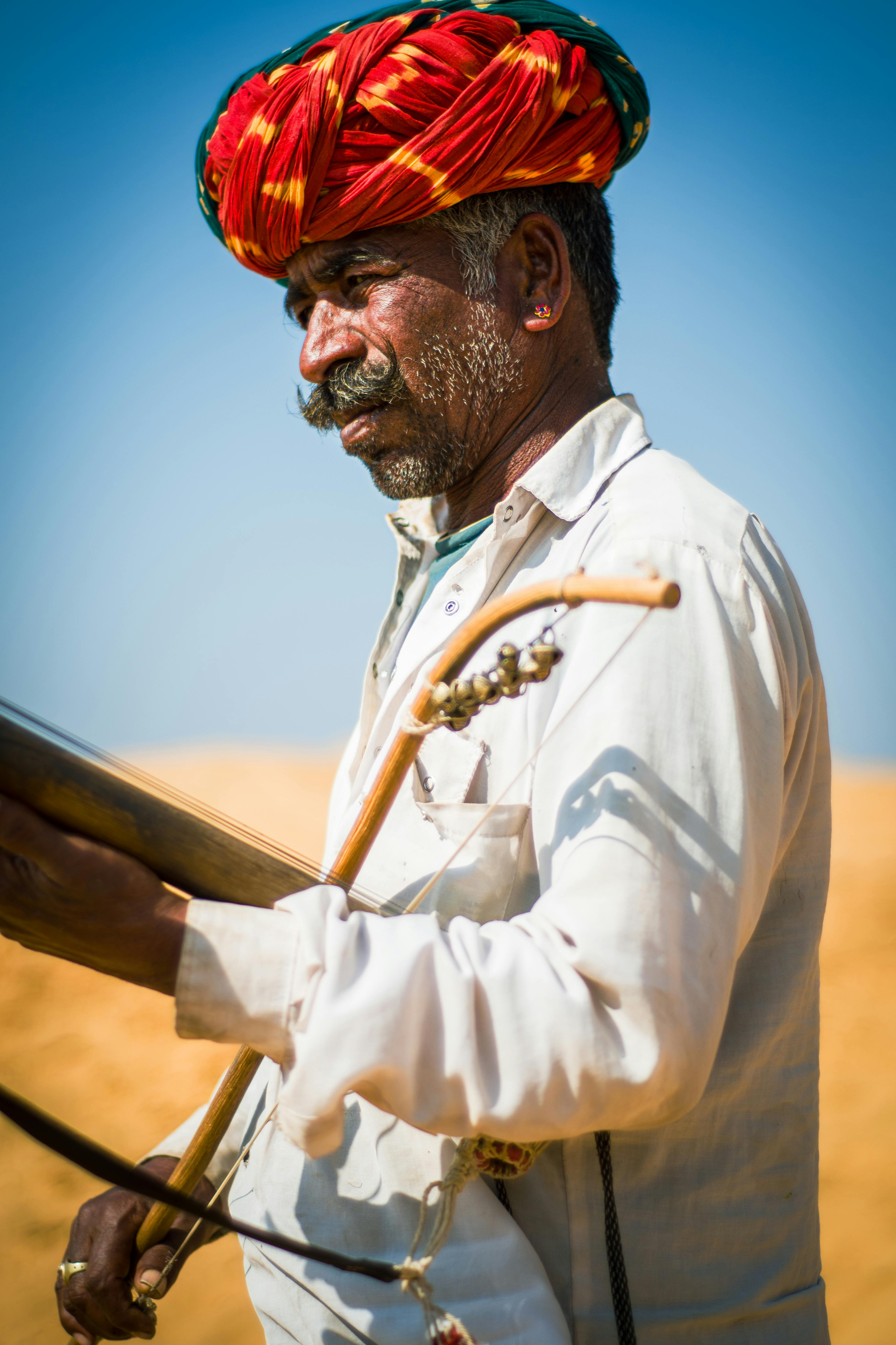 Portrait of a Rajasthani musician playing an instrument under the bright sun.