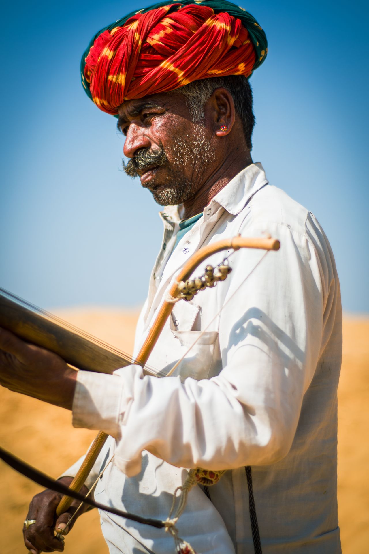 Rajasthani folk musician in a traditional turban performing at a desert camp
