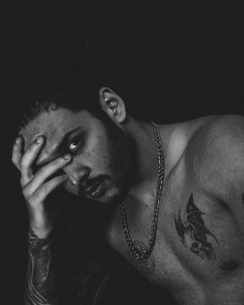 Free Artistic black and white portrait of a tattooed man with a contemplative expression. Stock Photo