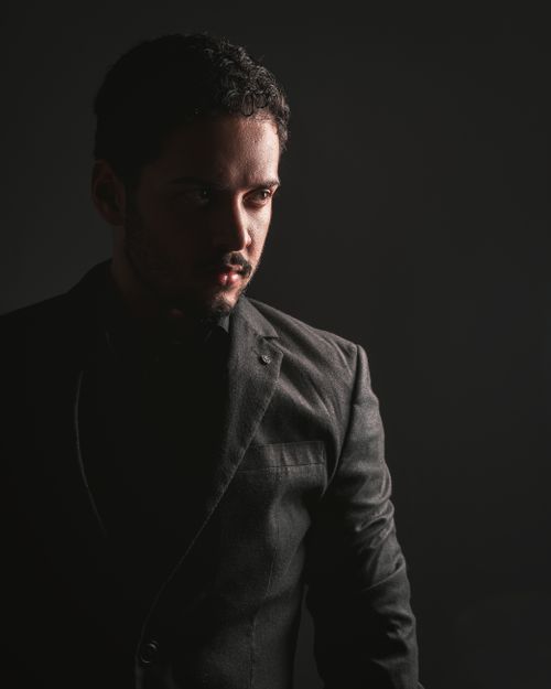 Free Dramatic portrait of a man in a suit with artistic lighting and deep shadows. Stock Photo