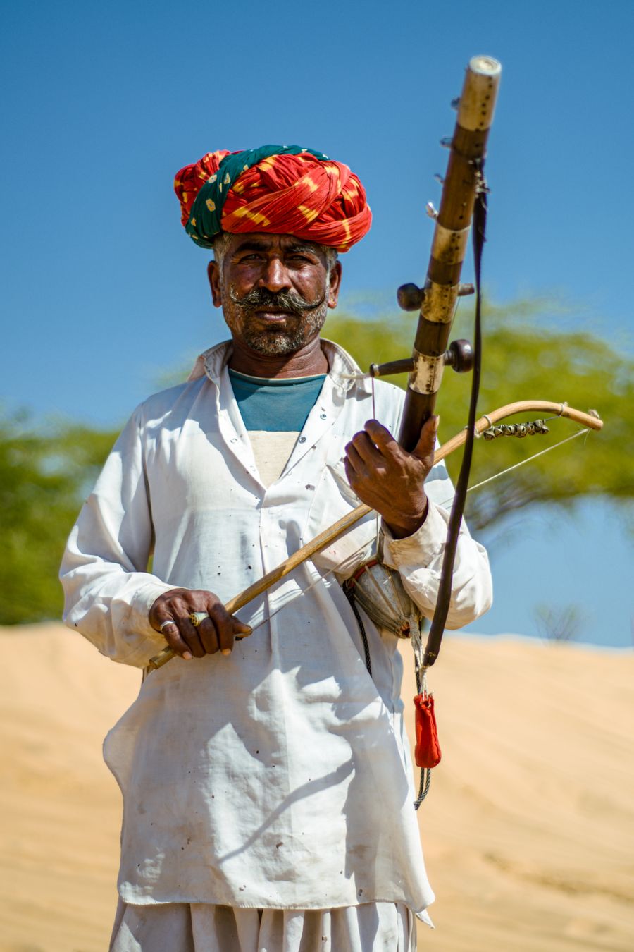 Rajasthani folk musician playing a traditional instrument in the desert