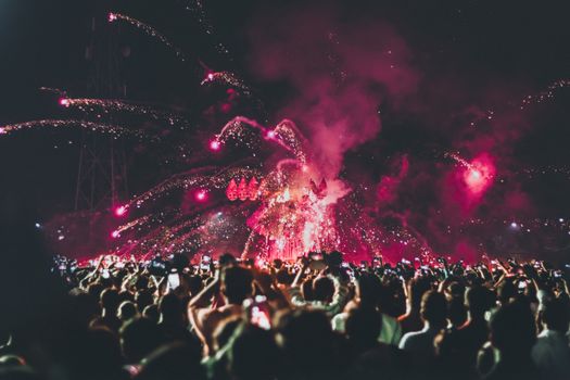 Crowd enjoying a vibrant fireworks display at an energetic night festival.