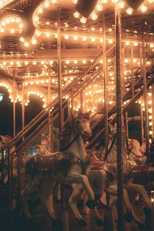 Free An enchanting night view of a vintage carousel with brightly lit horses and warm lights. Stock Photo