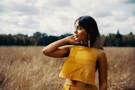 田野里，一位穿着时尚黄色服装的年轻女子优雅地站着