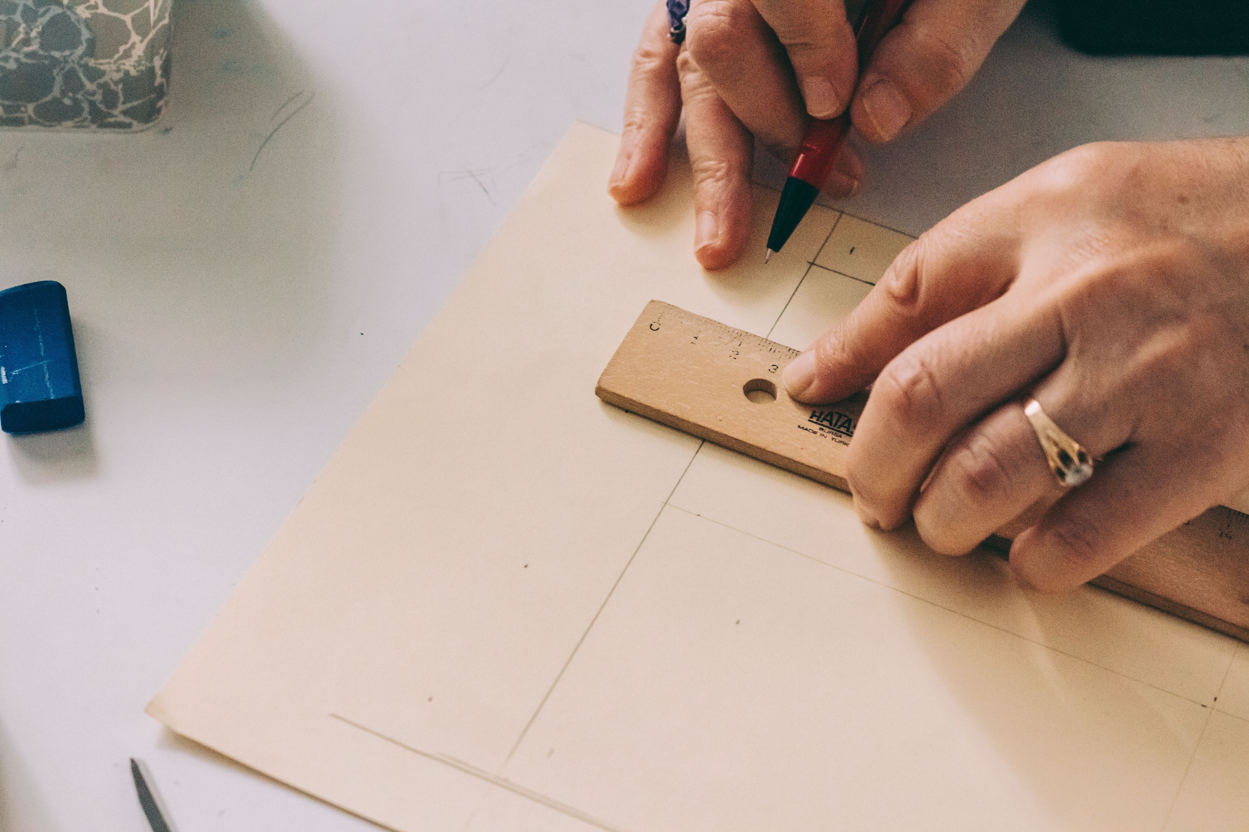 Close-up of hands using a ruler to draw lines on paper.