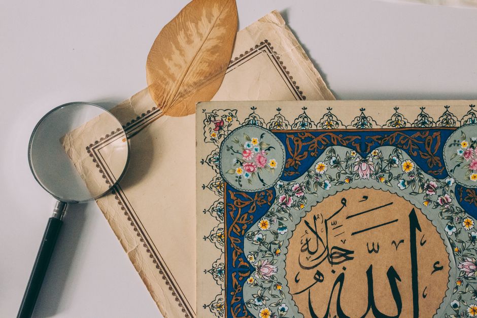 Islamic calligraphy art featuring intricate floral designs next to a magnifying glass.
