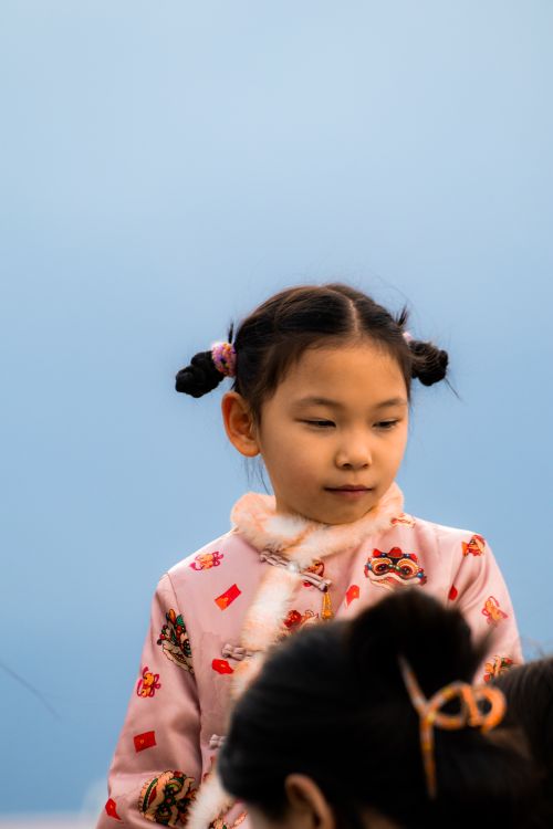 Free Young girl in Izmir wearing traditional pink clothing against a blue background. Stock Photo