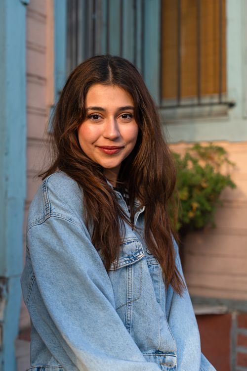 Free Portrait of a young woman smiling in a denim jacket with soft outdoor lighting. Stock Photo