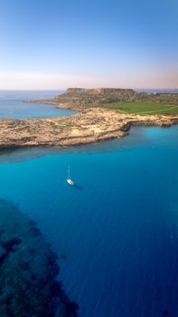 Explore the vibrant blue waters and rugged coastline of Cyprus with this breathtaking aerial view.