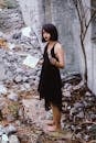 一名身穿黑色连衣裙的女子在废墟中手持一本书和一支蜡烛进行仪式