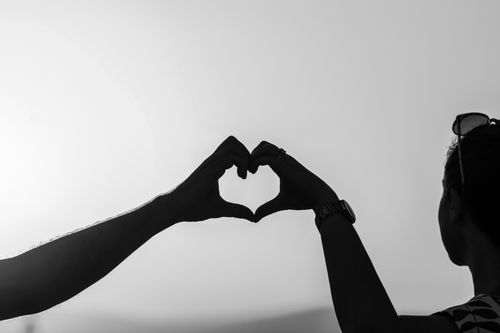 Free Black and white photo of a couple forming heart shape with hands, symbolizing love. Stock Photo