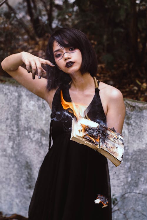Woman Holding Book on Fire