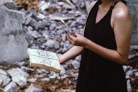 一名妇女在户外拿着蜡烛和咒语书进行神秘的仪式