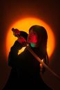 A captivating portrait of a samurai cosplayer with a sword, backlit by an intense red glow, creating an artistic ambiance.