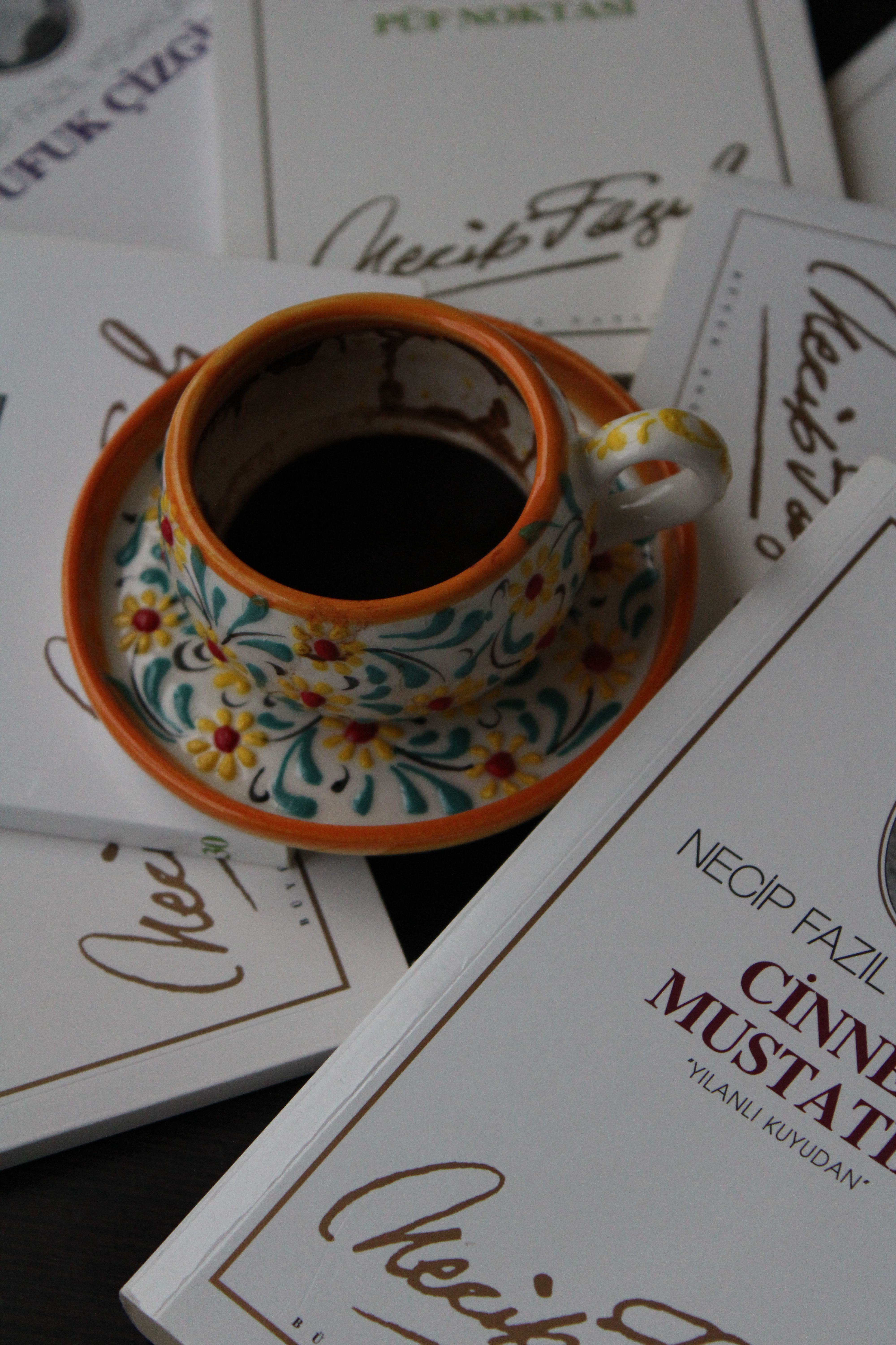 Colorful floral coffee cup with books featuring Necip Fazil's works.