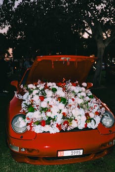 A vibrant red Porsche with an open hood filled with colorful flowers in Dubai.