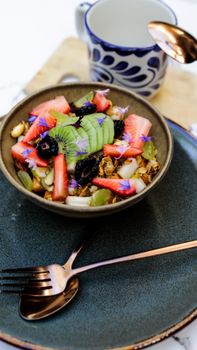 Colorful fruit and granola bowl with kiwi, strawberries, and blackberries close-up.