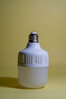 Minimalist design of a modern LED bulb against a simple yellow background.