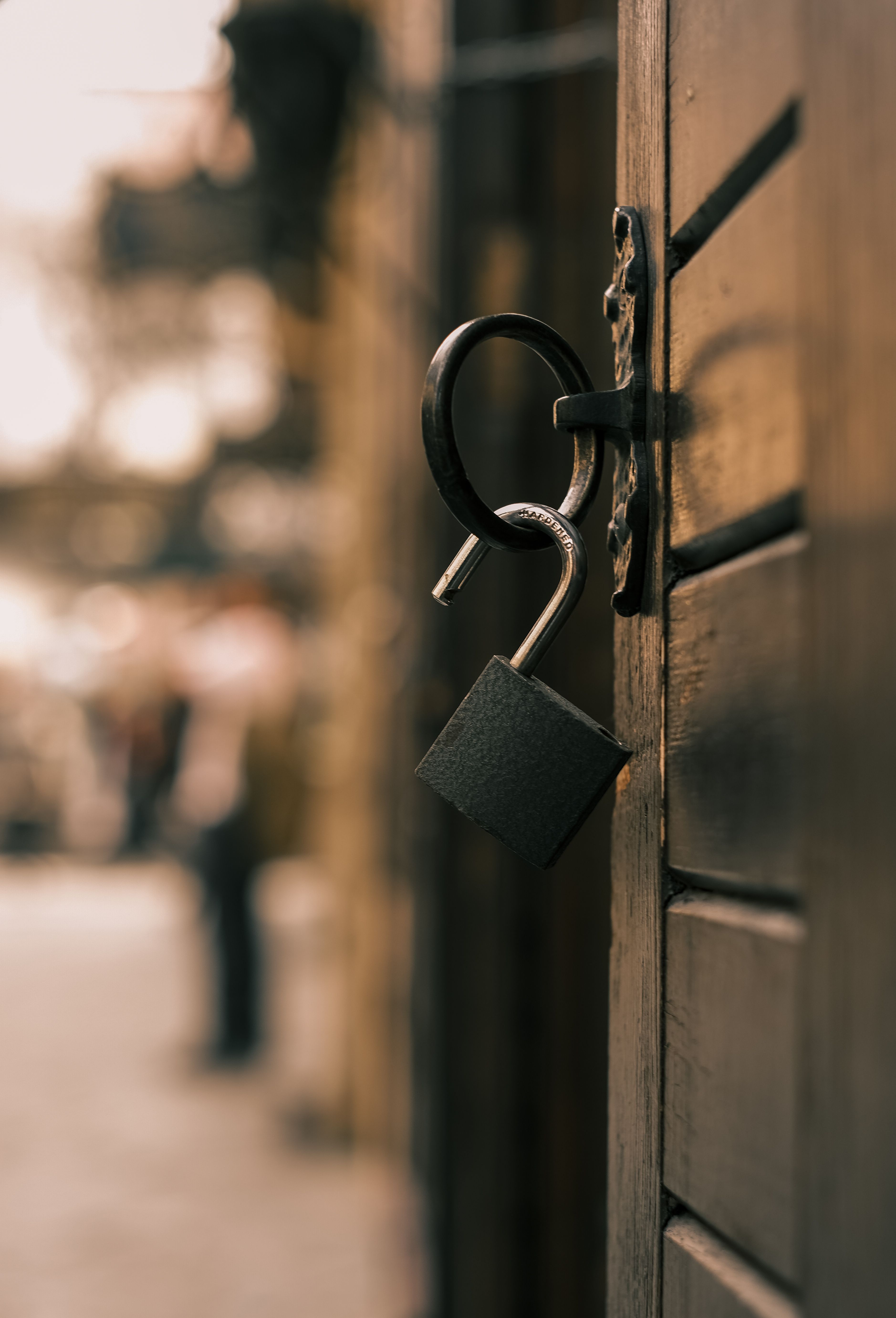 Free An unlocked padlock hanging on a wooden door in an urban setting, symbolizing security or freedom. Stock Photo