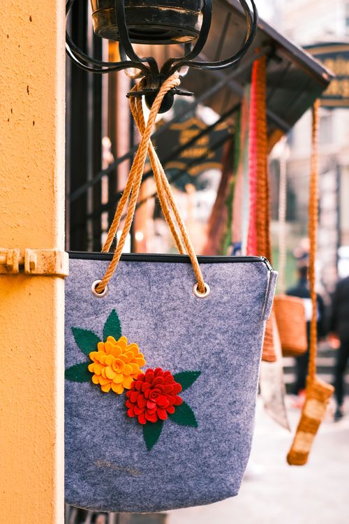 Free Vibrant blue felt bag with floral design hanging in a bustling street market. Stock Photo