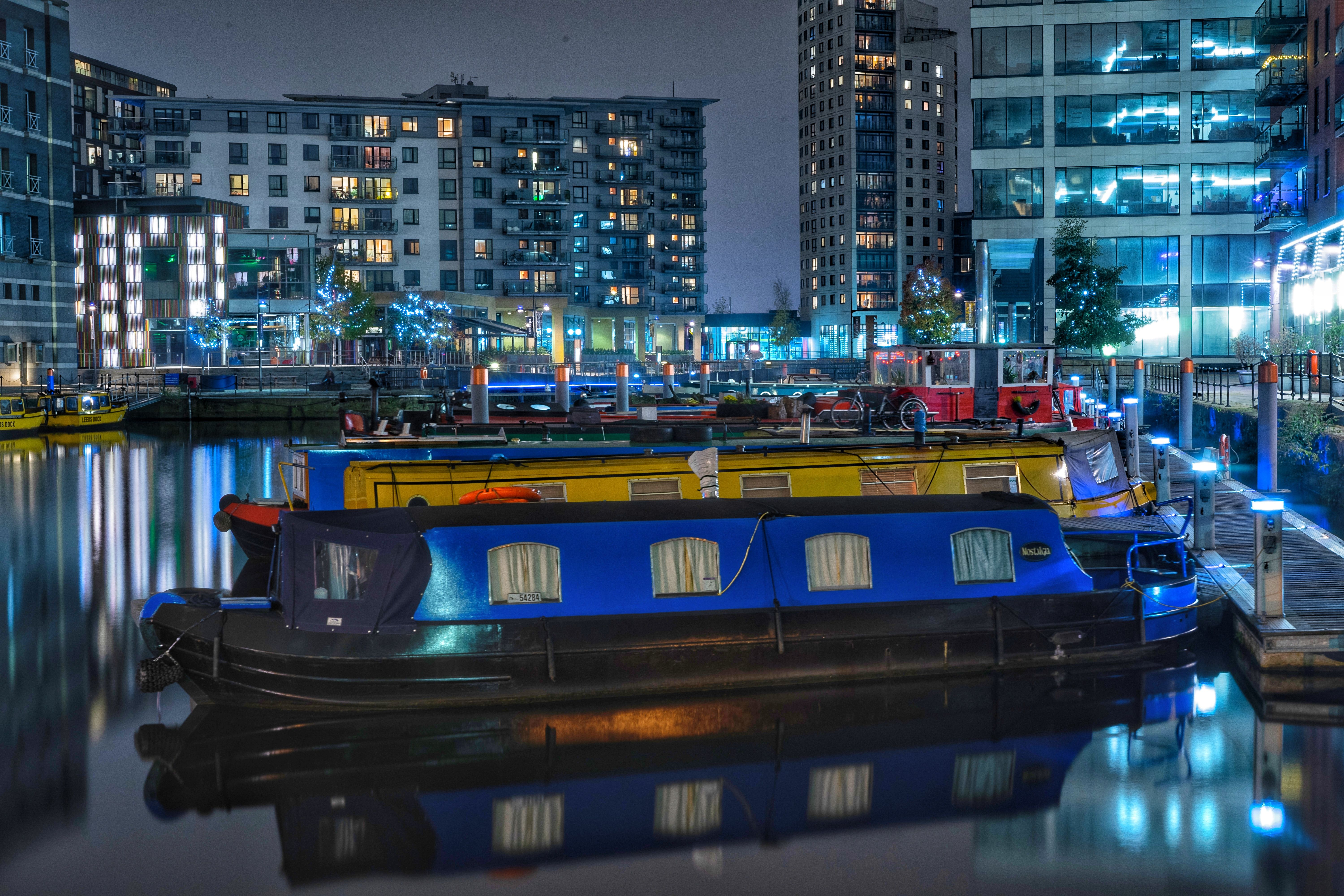 Vibrant city canal at night with illuminated boats and modern architecture.