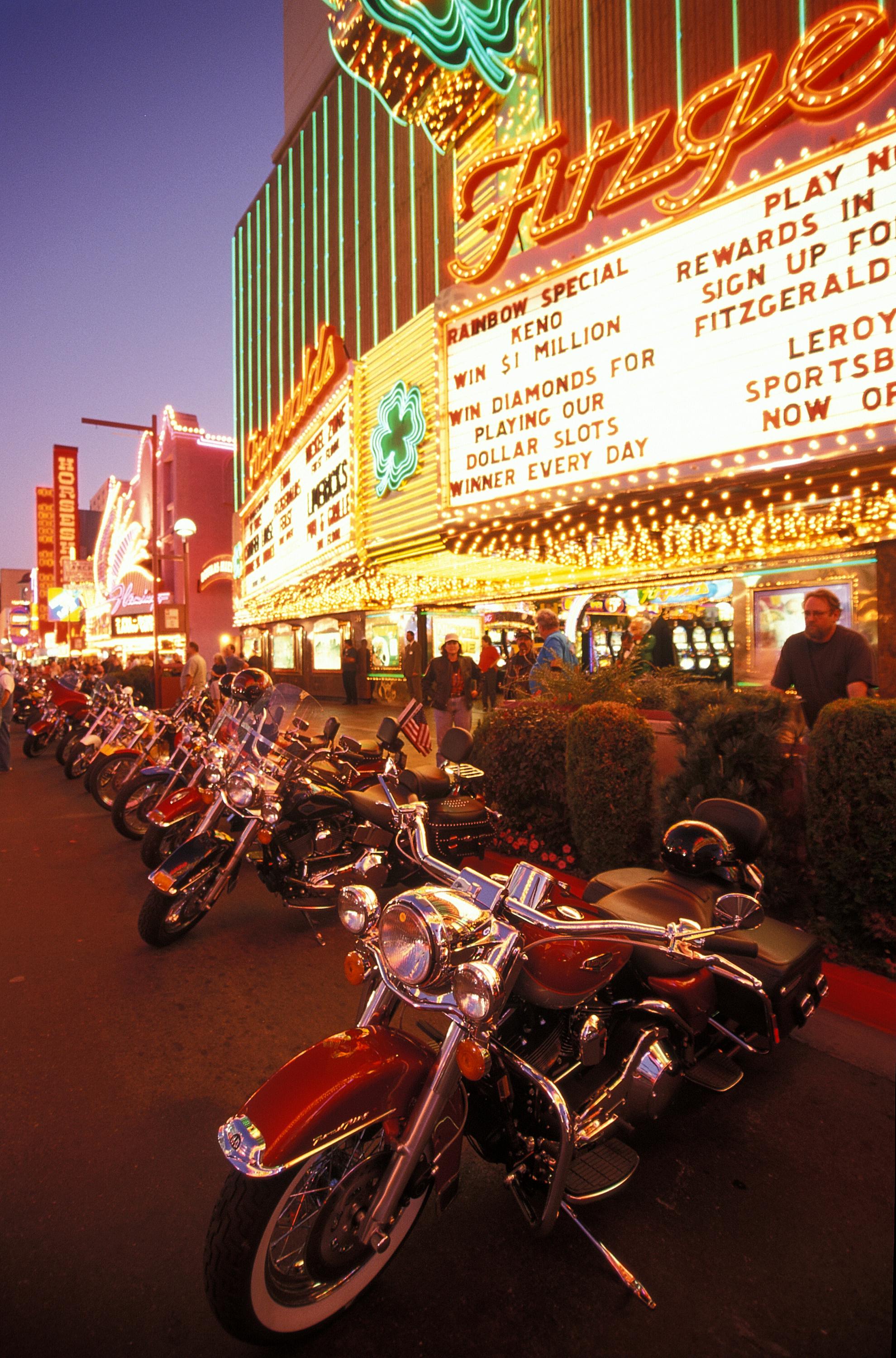 Vibrant scene of motorcycles lined up under bright neon signs in Reno, Nevada at night.