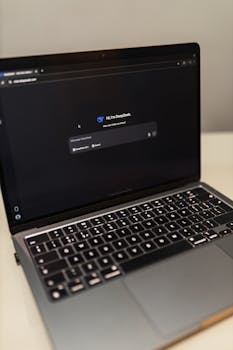 Close-up of a laptop showing an AI chat interface in a dimly lit room.