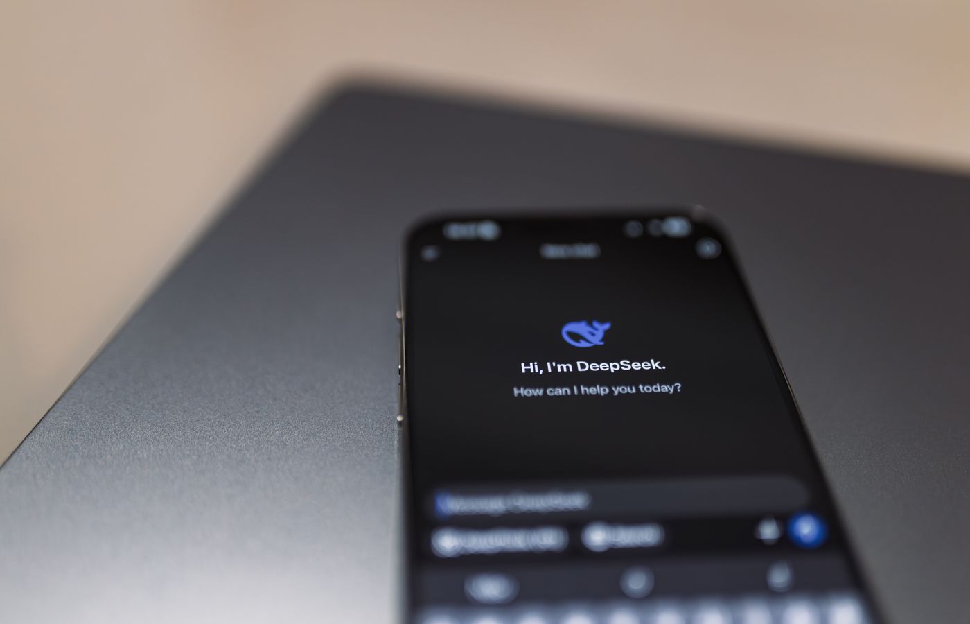 Close-up of a smartphone with AI assistant interface on screen over a laptop.