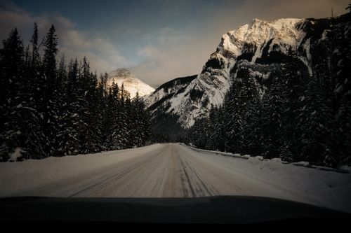 Free Snow-covered road through the majestic mountains and forest in Field, BC Stock Photo