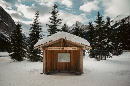 A snowy wooden shelter at Lake Louise with scenic mountains in the background.