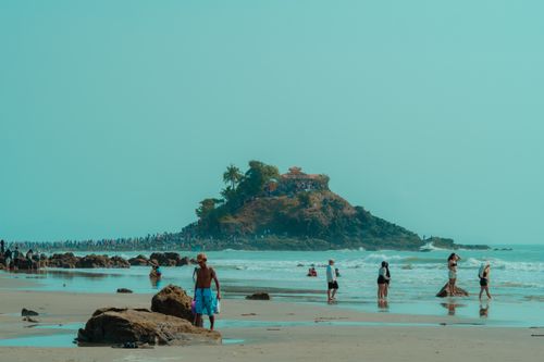 Free A lively beach scene with visitors enjoying the view of a nearby island. Stock Photo