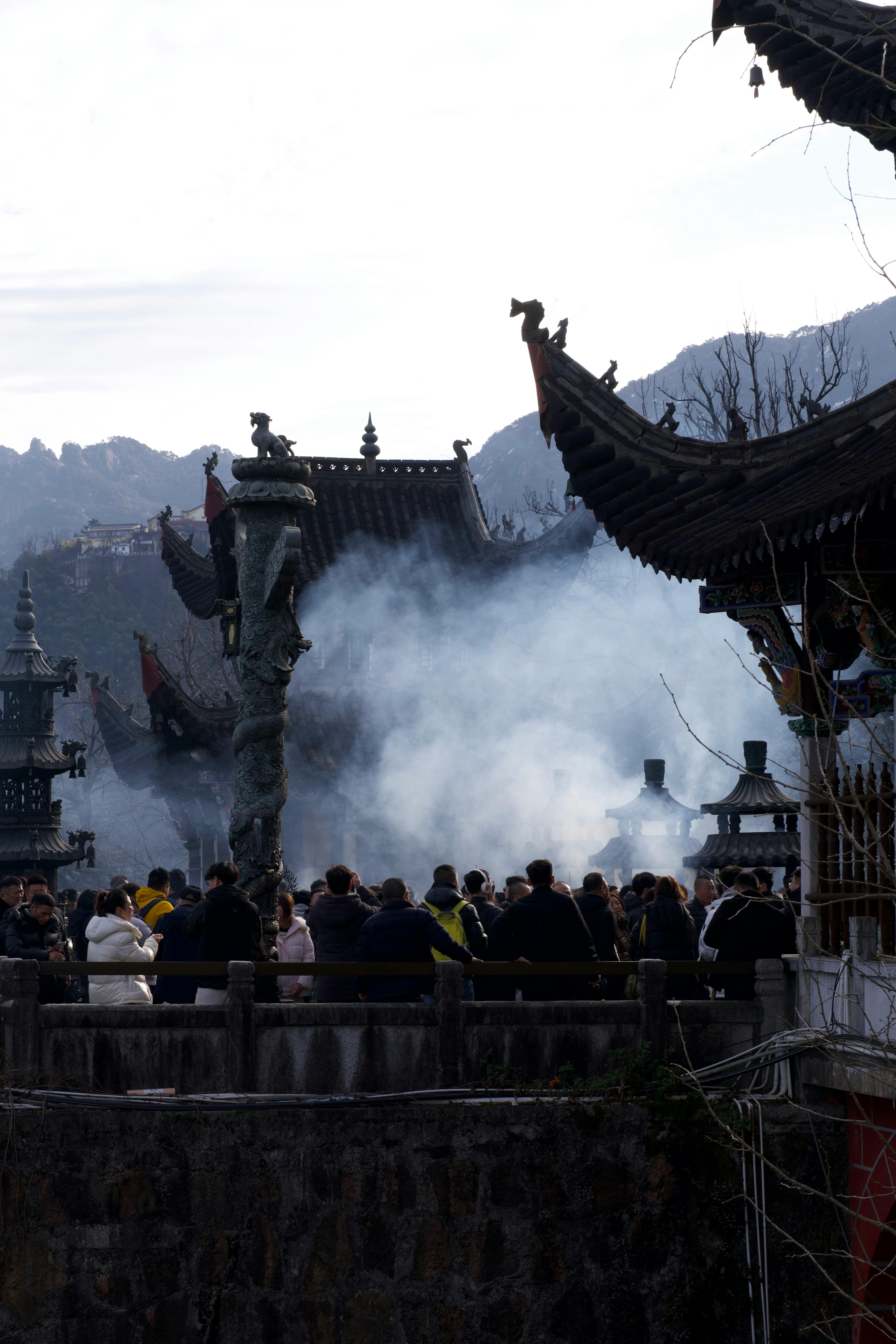 Crowded gathering at an ancient Asian temple under smoky skies, cultural ambiance.