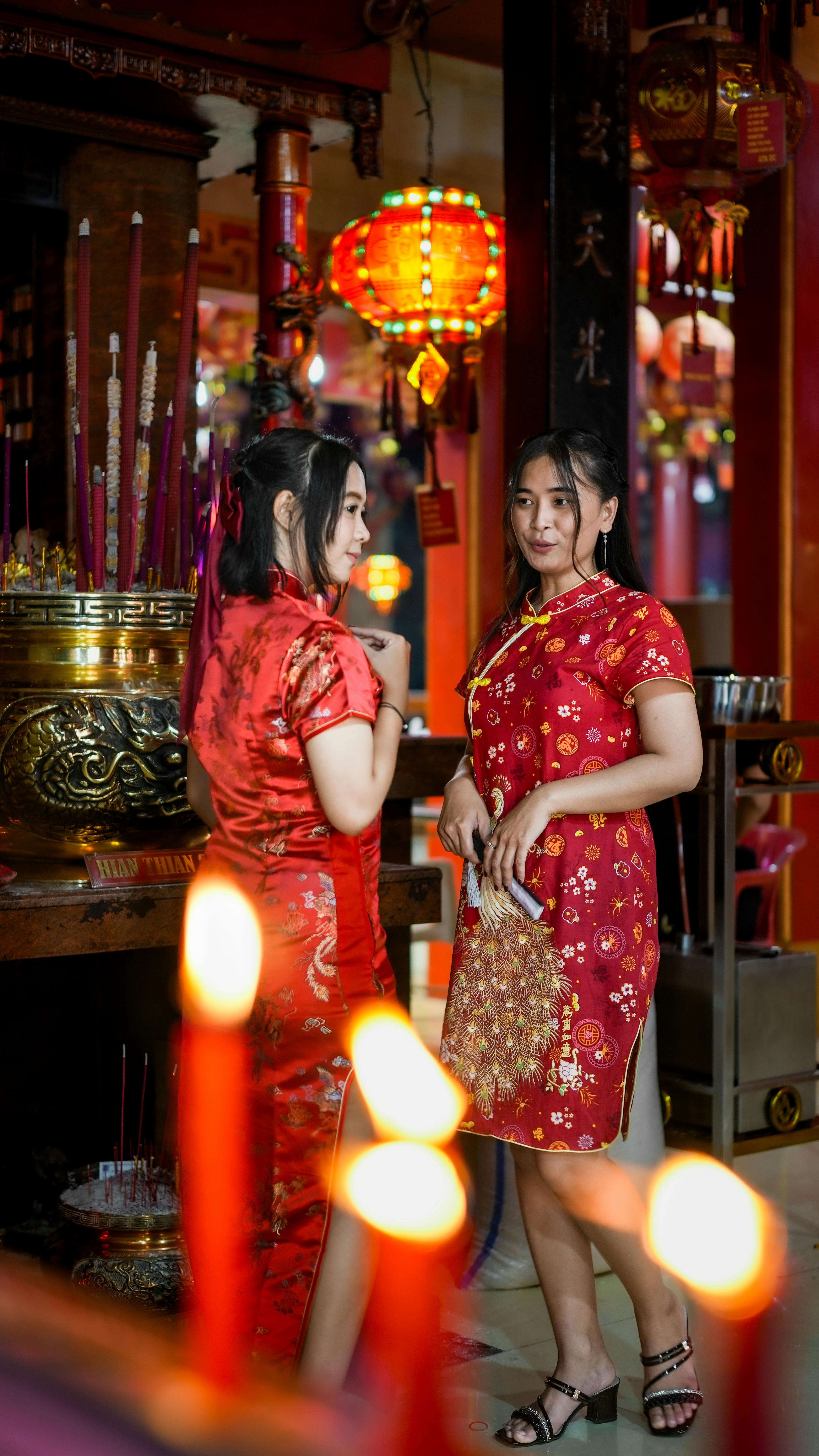 bezplatná Dvě ženy v tradičních cheongsamech slaví čínský Nový rok v chrámu. Základová fotografie