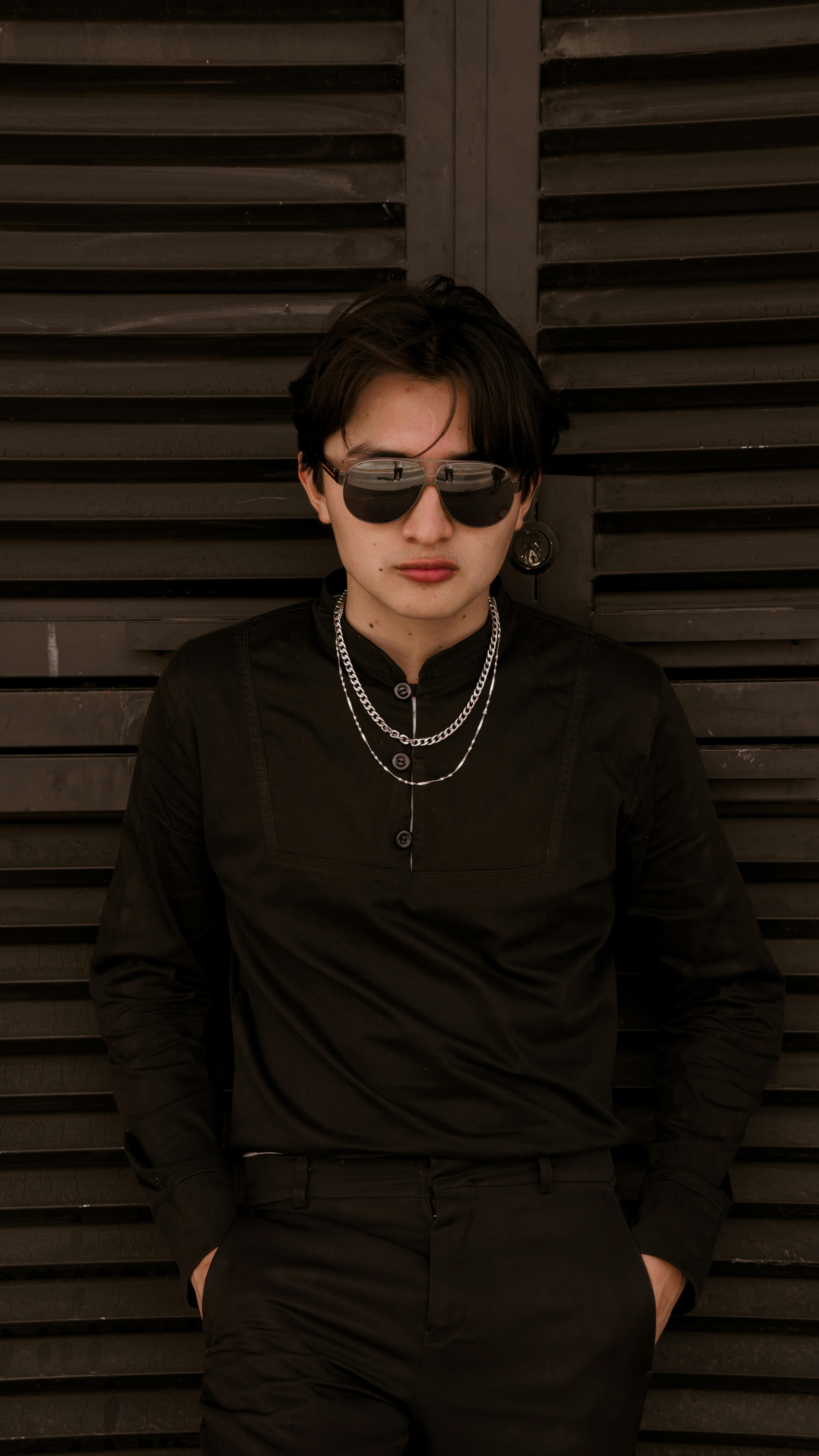 Fashionable young man wearing sunglasses against dark background. Urban style.