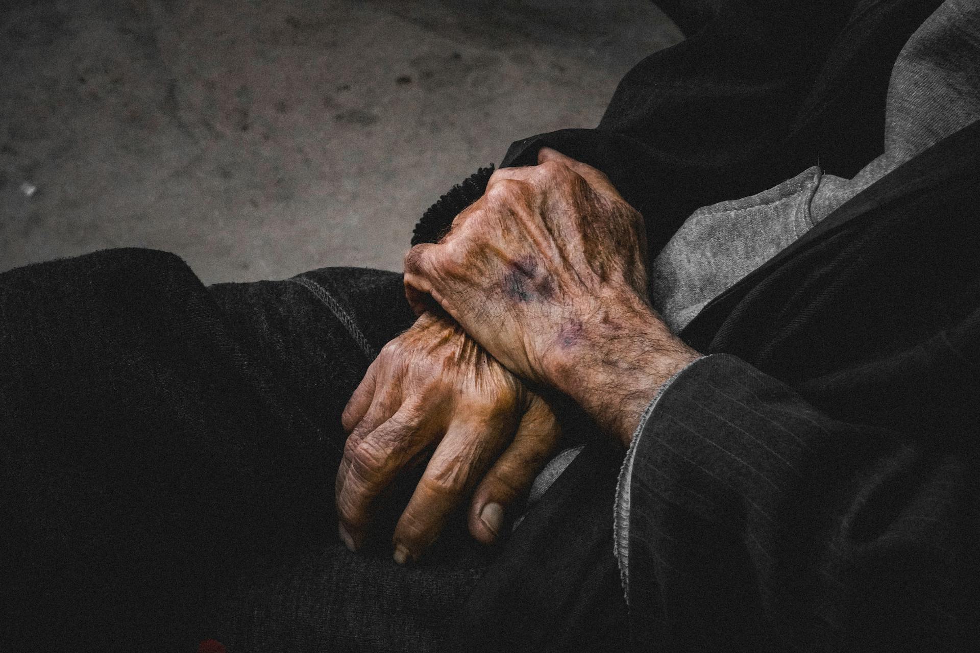 A close-up of elderly hands clasped together, showcasing age and resilience.