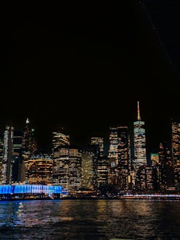 Stunning view of the New York City skyline illuminated at night, reflecting on water.