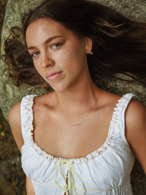 Free A serene portrait of a woman lying on a rock outdoors in natural light. Stock Photo
