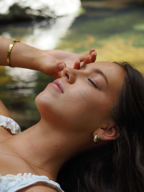 Free Peaceful woman relaxing outdoors by a serene stream, embodying tranquility and nature. Stock Photo