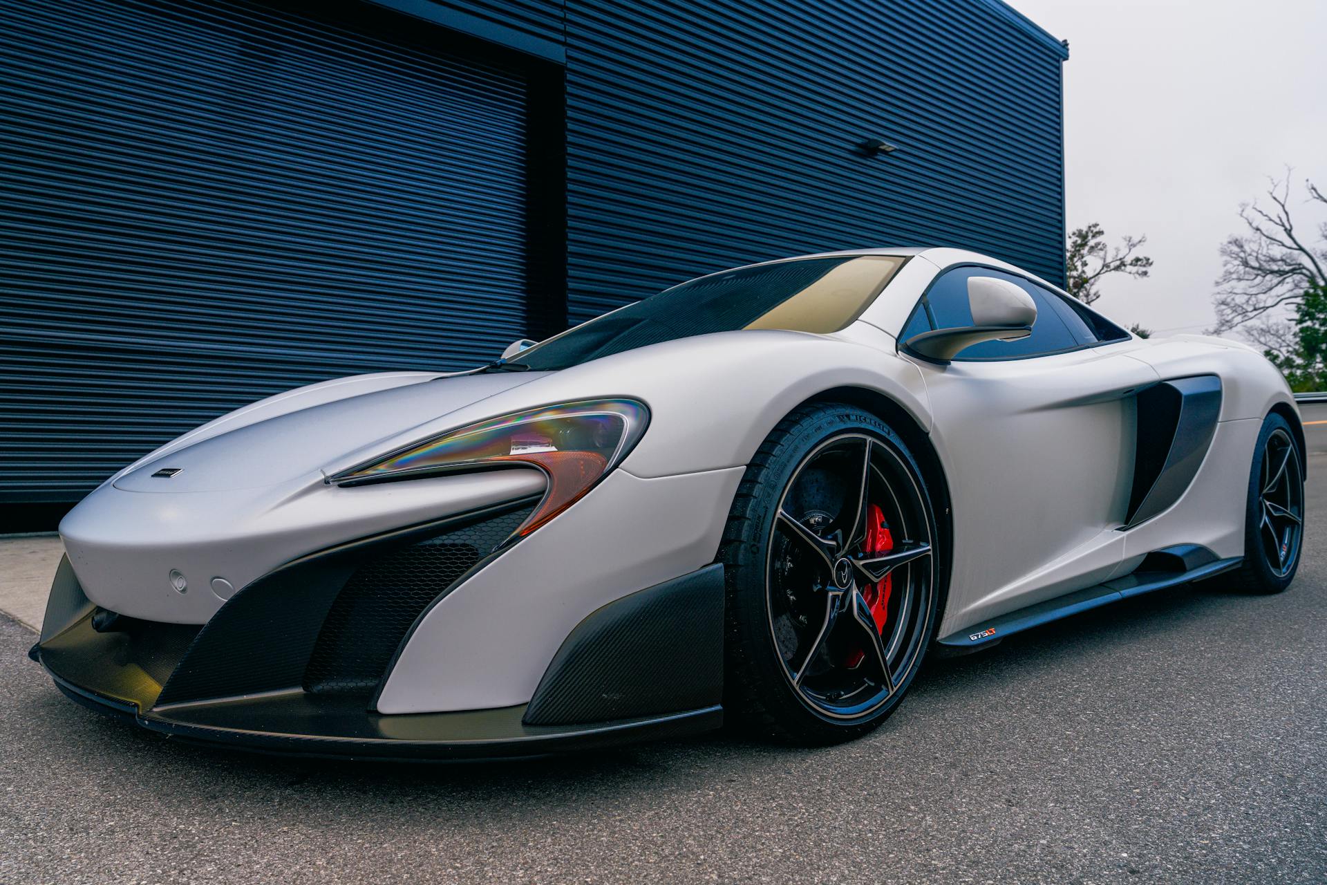 A silver sports car parked outside a modern building, showcasing sleek design.