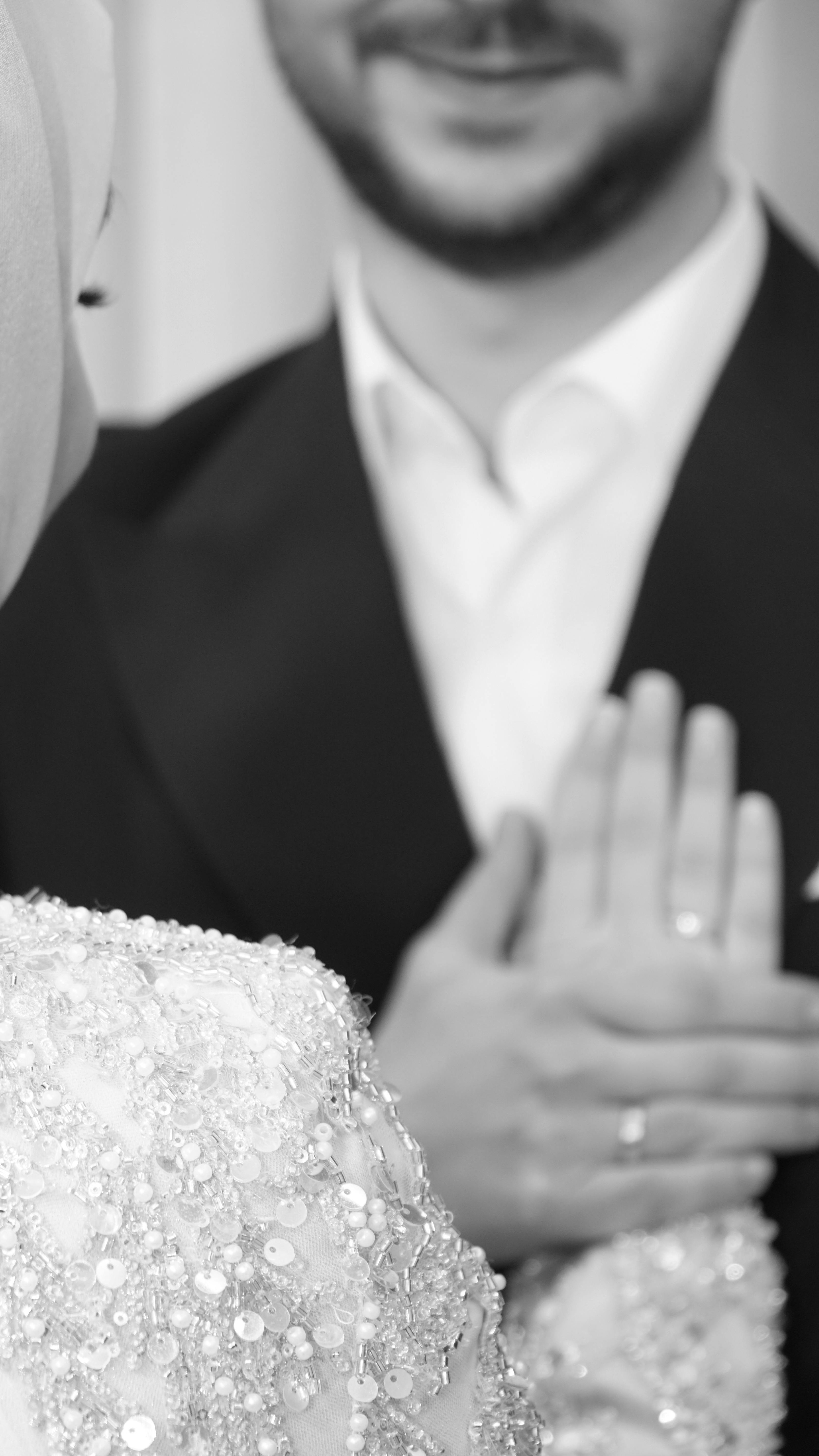 Close-up of couple's hands and smiles in black and white engagement photo.