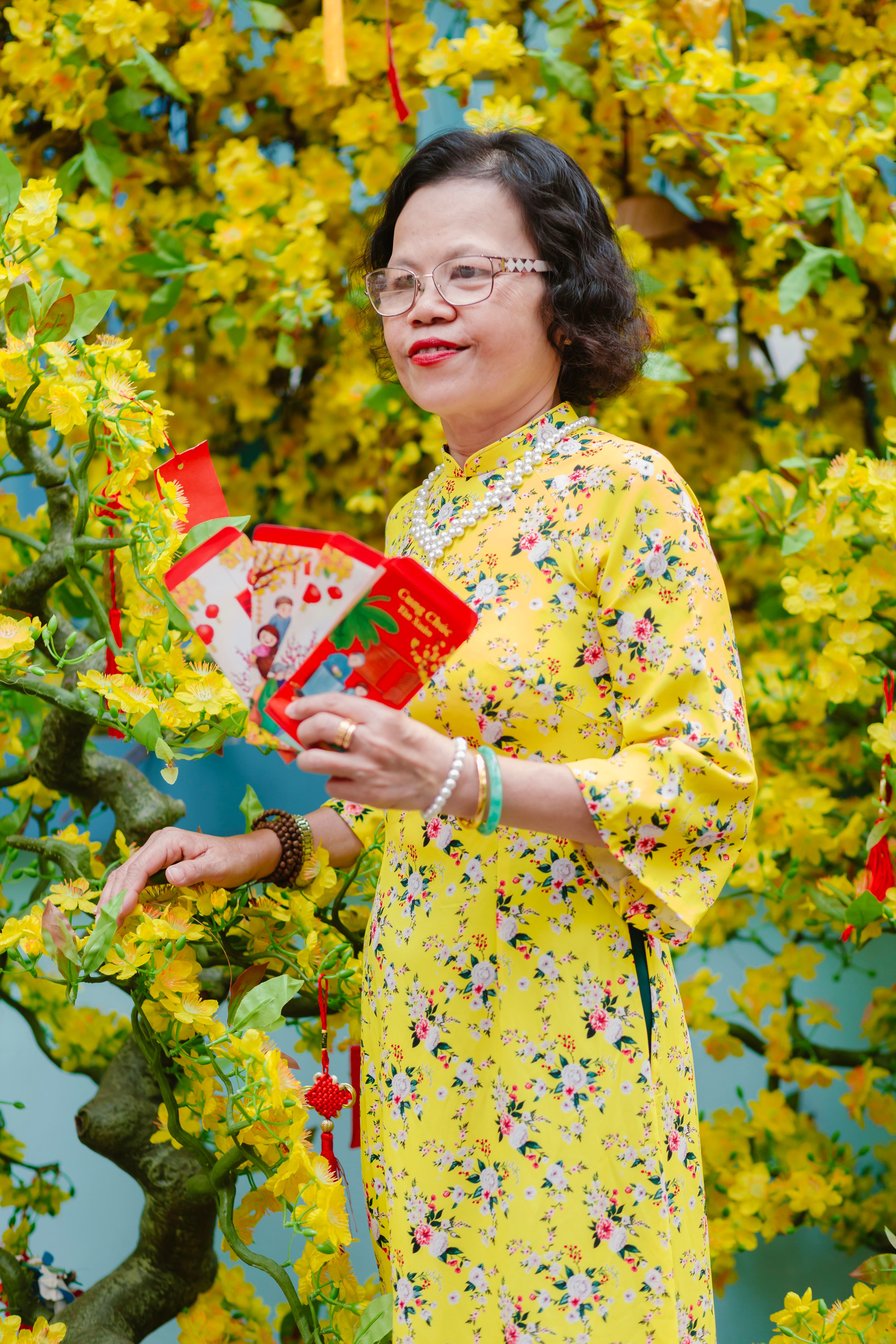 Woman in a floral dress holding red envelopes for Lunar New Year celebration.