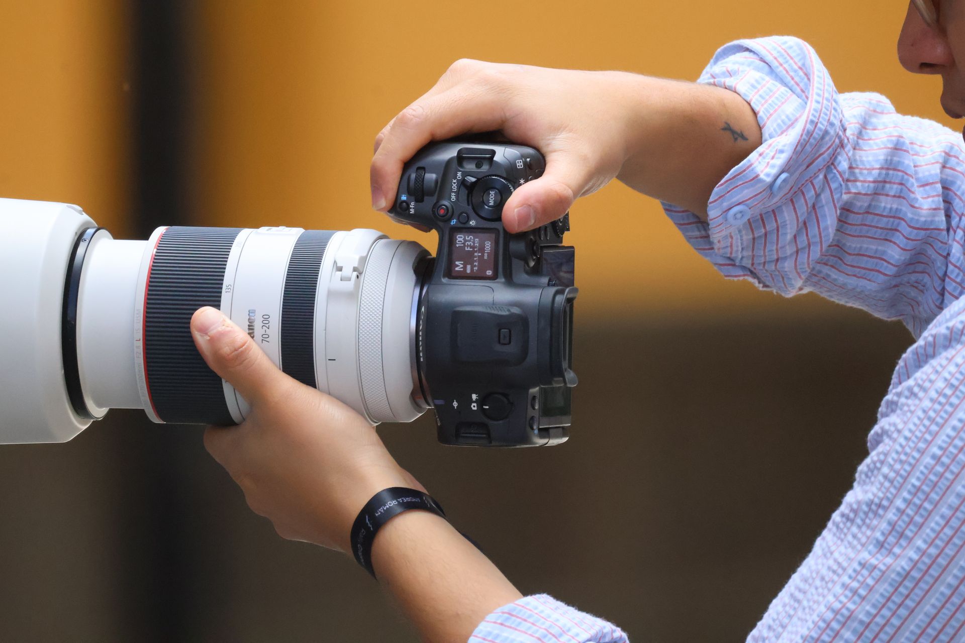 Close-up of a photographer holding a DSLR camera with a zoom lens, focusing on details and precision.