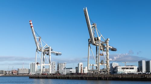 Free Wide view of shipping cranes against Hamburg skyline under clear blue sky. Stock Photo
