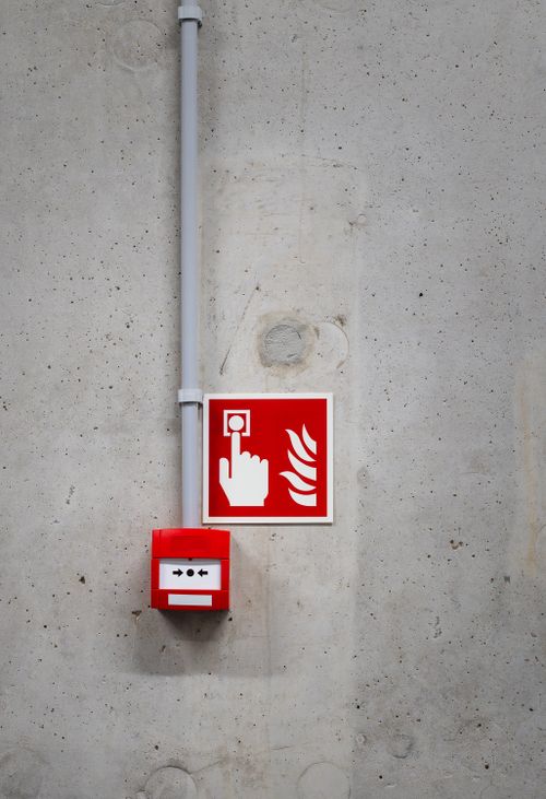 Free A red fire alarm switch with a warning sign on a concrete wall, highlighting safety in industrial settings. Stock Photo