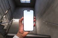 Hand Holding Smartphone with Blank Screen in Stairwell
